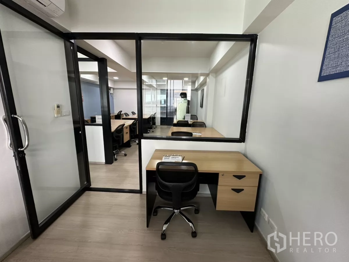 办公空间 出租在Watthana, Bangkok - 玻璃门旁的小型工位，内窗可望向主办公区。