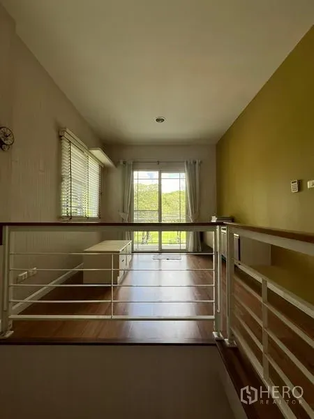 Detached House for rent in Bang Kapi, Bangkok - Upstairs landing with wood floors and sliding doors to a balcony overlooking greenery.