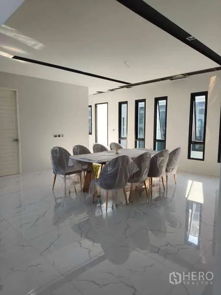 Detached House for rent in Phra Khanong, Bangkok - Dining room set for eight on marble flooring with slim vertical windows.
