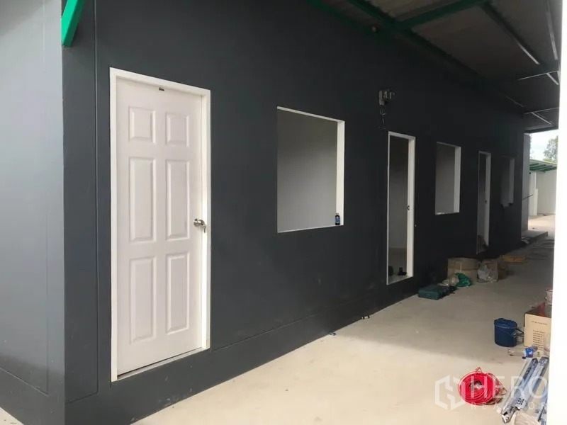 Factory for rent or sale in Mueang Samut Sakhon, Samut Sakhon - Side service building with multiple access doors and a sheltered walkway.