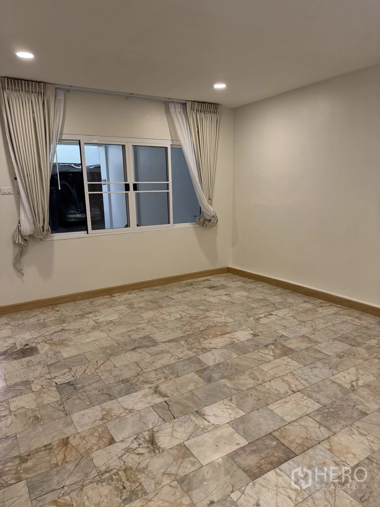 Townhouse for rent or sale in Yan Nawa, Bangkok - Empty room with marble tile floor, recessed lights, and window with curtains.