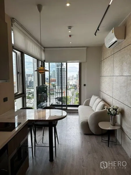 公寓 出租在Watthana, Bangkok - 采光充足的客厅，连接阳台，开放式岛台厨房与城市景观。