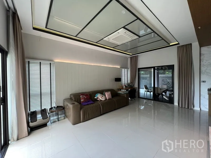 Townhouse for rent in Saphan Sung, Bangkok - Spacious living room with glossy tiled floors, recessed lighting, and sliding doors to the patio.