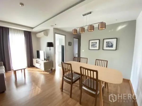 公寓 出租在Huai Khwang, Bangkok - 采光良好的客餐厅，木地板，六人餐桌、电视柜与阳台窗帘。