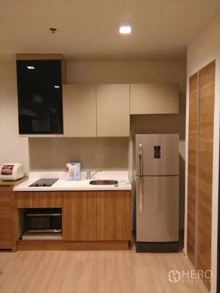 Condominium for rent in Sathon, Bangkok - Modern kitchenette with cooktop, microwave and full-size refrigerator.