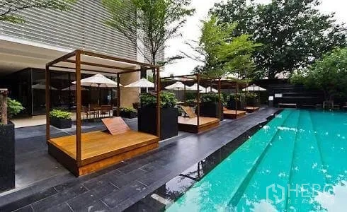 公寓 出租或出售在Khlong Toei, Bangkok - 户外游泳池，木质凉亭与躺椅，绿化环绕。