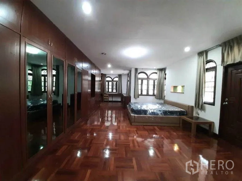 Detached House for rent in Watthana, Bangkok - Extra‑large master bedroom with a full wall of built‑in wardrobes and glossy parquet flooring.