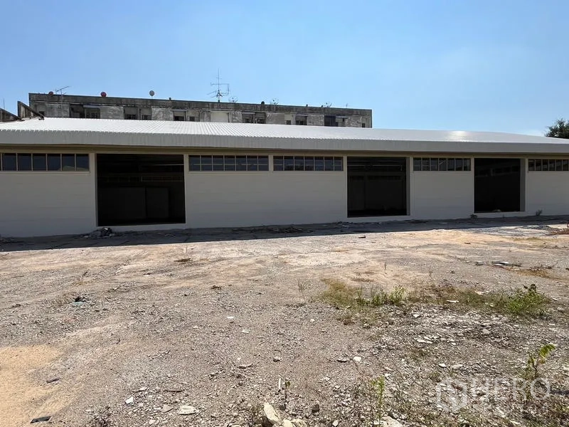 Warehouse for rent or sale - Long warehouse facade with multiple roller doors and clerestory windows.