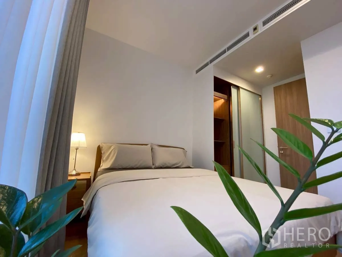คอนโด for rent in Watthana, Bangkok - มุมห้องนอนมีเตียง โคมไฟข้างเตียง ต้นไม้ในห้อง และตู้เสื้อผ้าแบบวอล์กอิน