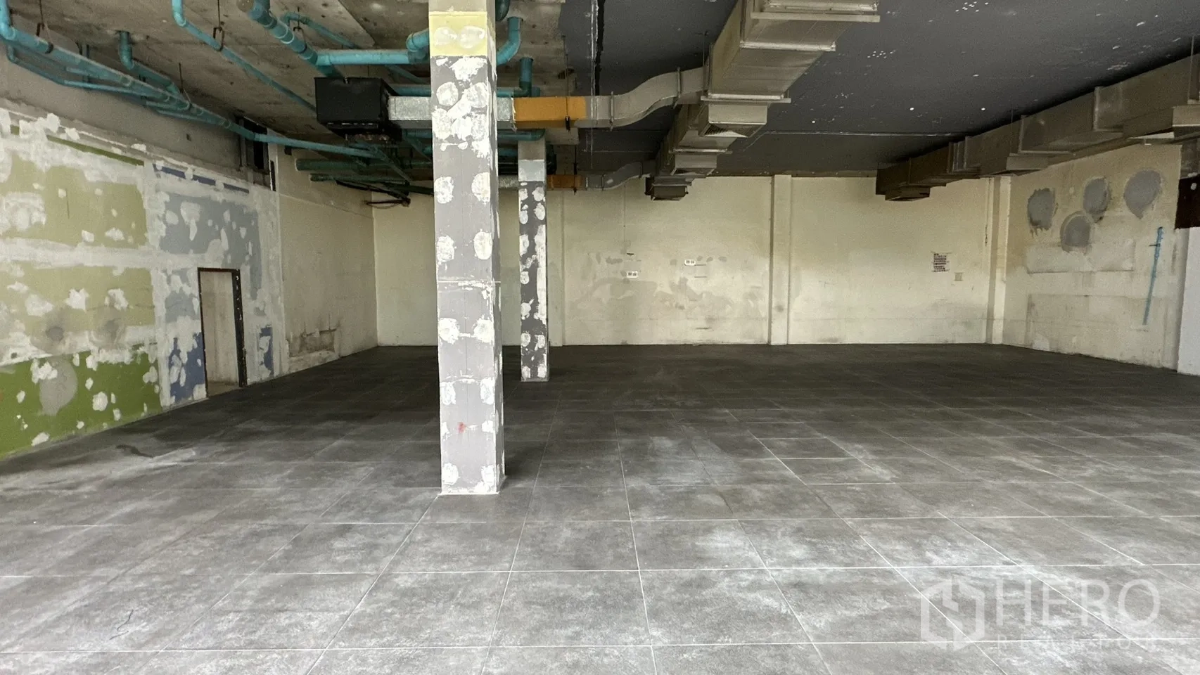 พื้นที่ขายของ for rent in Watthana, Bangkok - เสากลางกับผนังฉาบปะ และท่อสาธารณูปโภคสีน้ำเงินบนเพดาน.