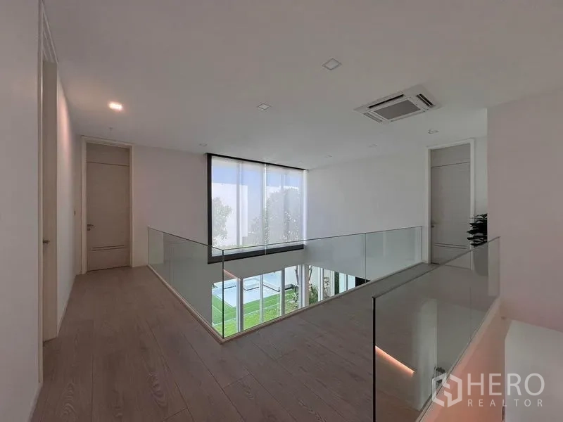 Detached House for sale in Samut Prakan - Upper landing with glass balustrade overlooking the living area and garden.