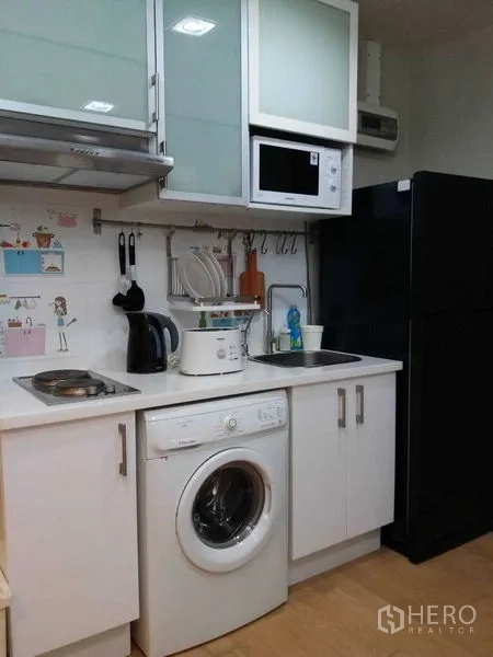 公寓 出售在Watthana, Bangkok - 紧凑厨房，炉灶、微波炉、冰箱及室内洗衣机。