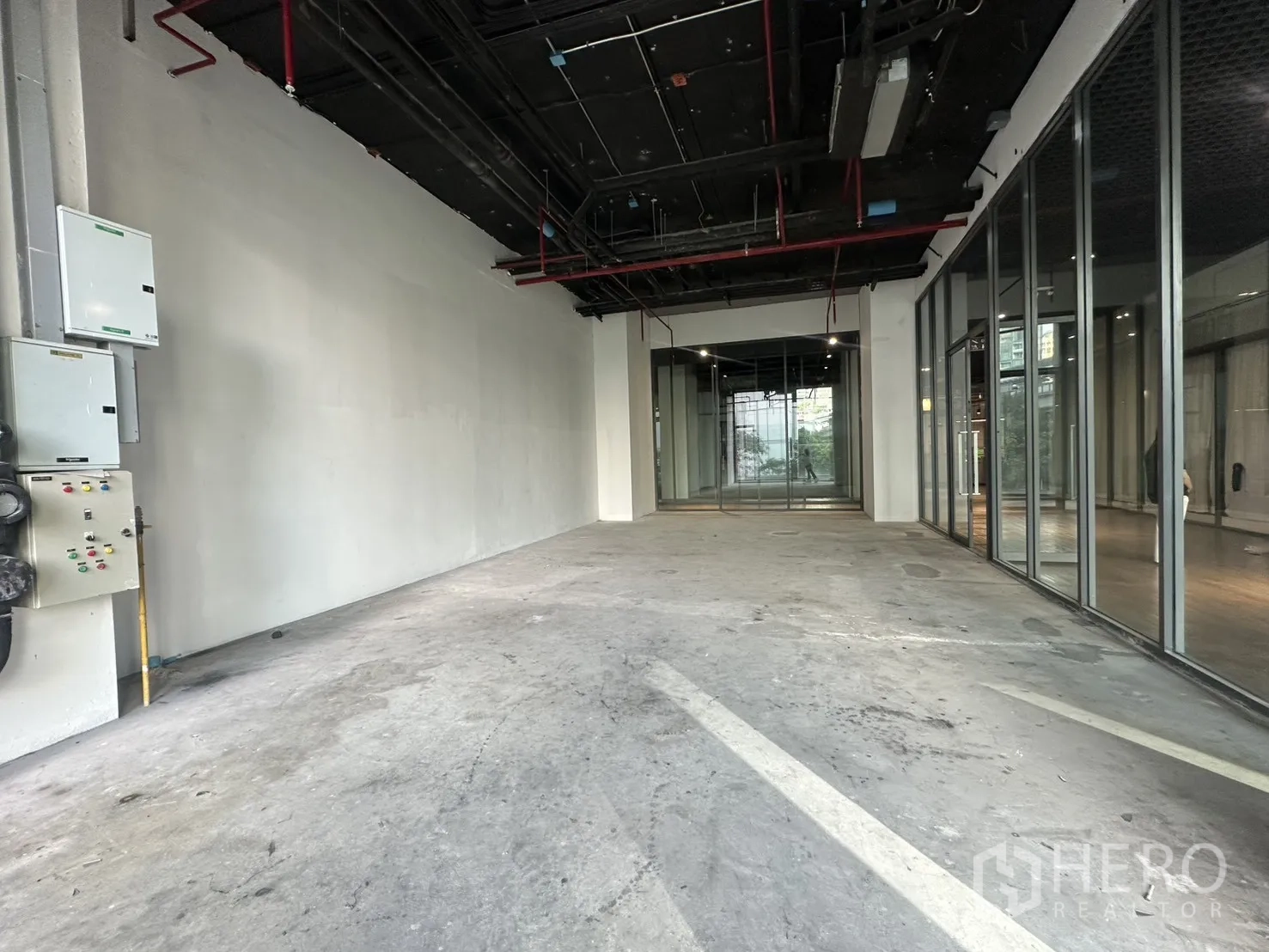 零售空间 for rent in Khlong Toei, Bangkok - 内部纵深空间，白色墙面、外露管线与玻璃隔断。