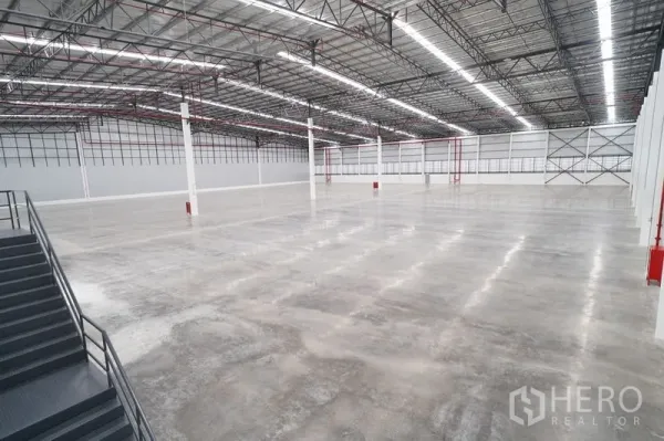 Warehouse for rent in Khlong Luang, Pathum Thani - Expansive warehouse hall with polished concrete floor, high steel truss ceiling, and long LED light strips.