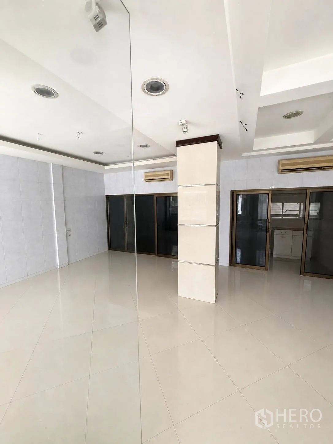 店屋 for rent in Bang Rak, Bangkok - 明亮的开放式底层，白色亮面地砖、嵌入式天花灯、空调与玻璃隔断。