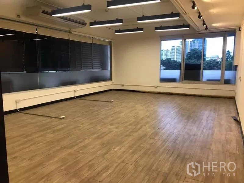 Office Space for rent in Khlong Toei, Bangkok - Corner office area with large windows, city views, wood-look floors, and linear pendant lighting.