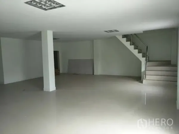 Factory for rent or sale in Bang Phli, Samut Prakan - Open-plan ground floor workspace beside stairs and recessed ceiling lights.