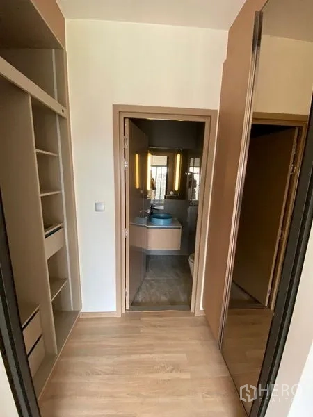 公寓 出租或出售在Watthana, Bangkok - 走廊设嵌入式柜体，通向配蓝色面盆的浴室。