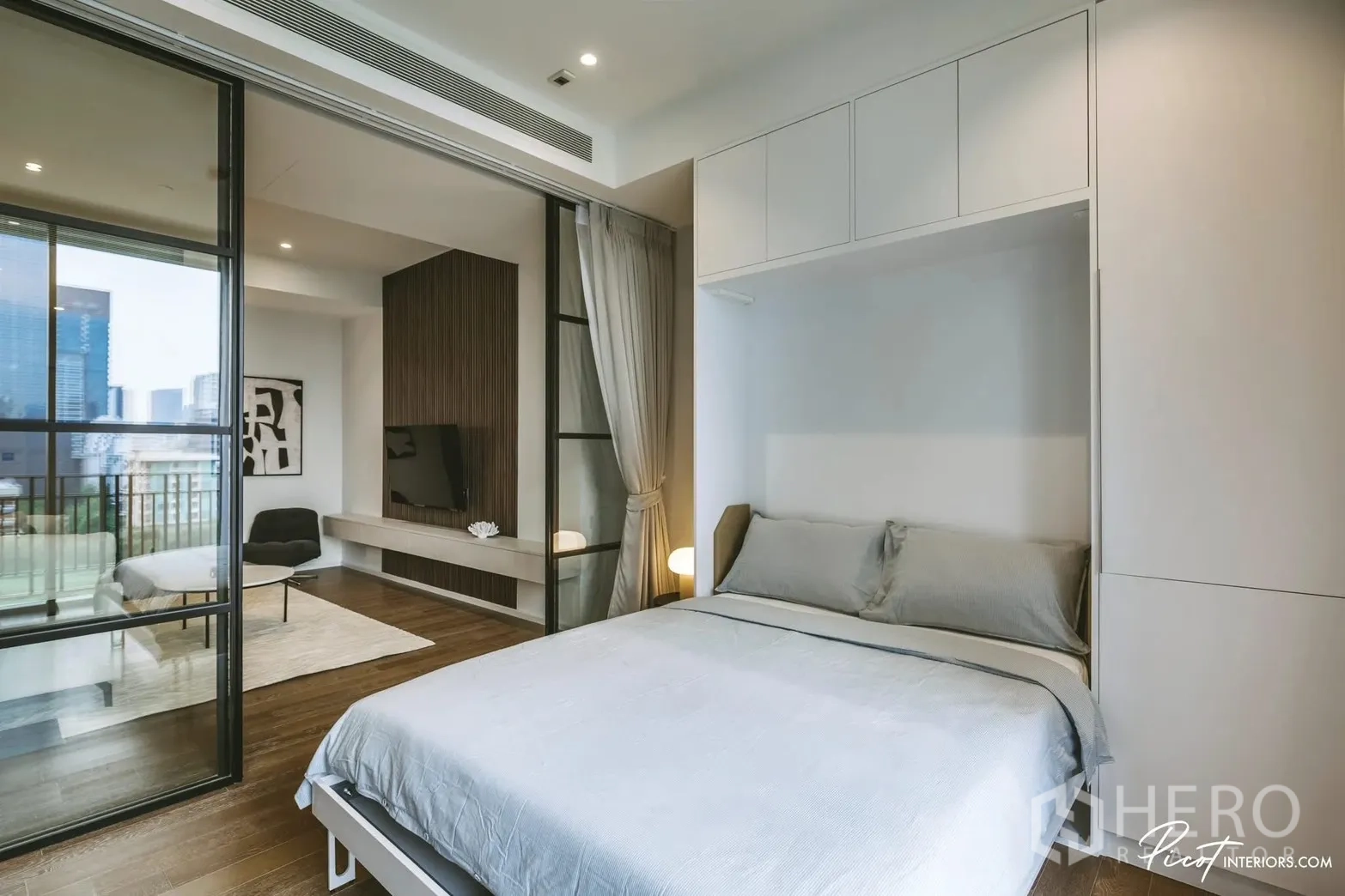 คอนโด for rent in Pathum Wan, Bangkok - ห้องนอนกั้นด้วยประตูกระจกเลื่อนไปยังห้องนั่งเล่น มีเตียงคู่และมุมชมวิวเมือง
