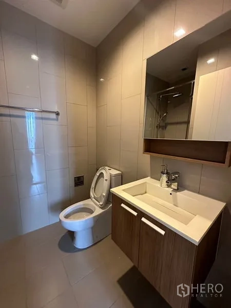 Condominium for rent in Watthana, Bangkok - Second bathroom with vanity, mirror cabinet, and toilet in neutral tones.