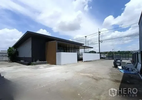 Warehouse for rent in Prawet, Bangkok - Paved yard with office-style outbuilding and gated street access, suitable for multiple parking spaces.