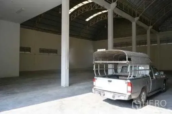 Warehouse for rent in Samut Sakhon - Spacious warehouse interior with high arched steel roof, concrete floor and a pickup truck.