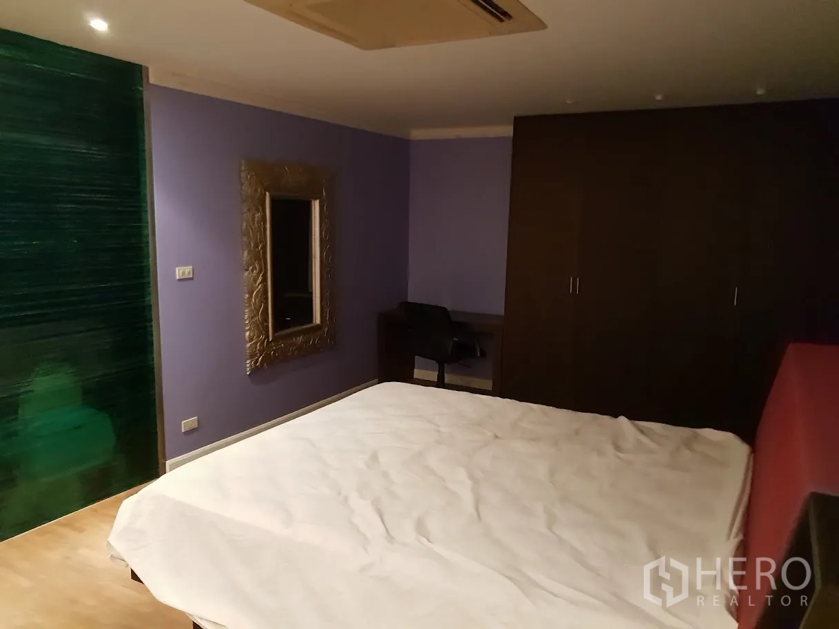 Condominium for rent in Yan Nawa, Bangkok - Bedroom with a purple accent wall, green glass feature panel, desk and built‑in wardrobe.