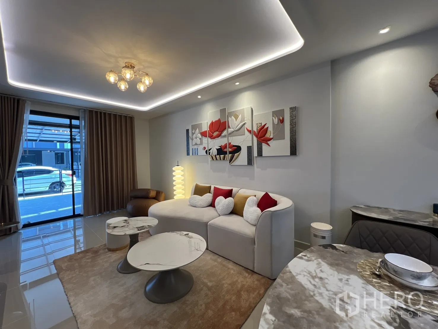 ทาวน์เฮาส์ for rent in Bang Phli, Samut Prakan - ห้องนั่งเล่นสว่างด้วยโซฟาโค้ง โต๊ะกลาง หน้าต่างบานใหญ่ และไฟซ่อนไลท์รอบเพดาน
