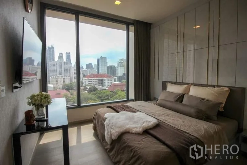 公寓 出售在Watthana, Bangkok - 卧室大幅落地窗，欣赏素坤逸城市天际线，对面为电视。