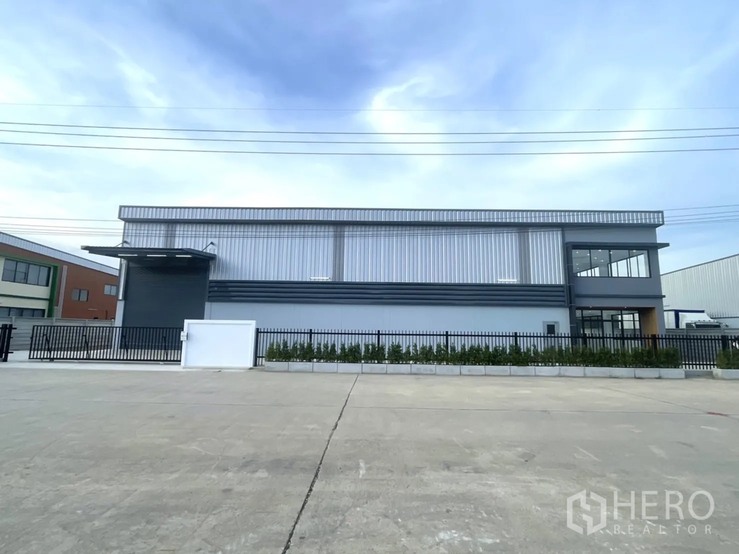 Factory for rent or sale in Bang Yai, Nonthaburi - Full facade view of modern factory and landscaped planters.