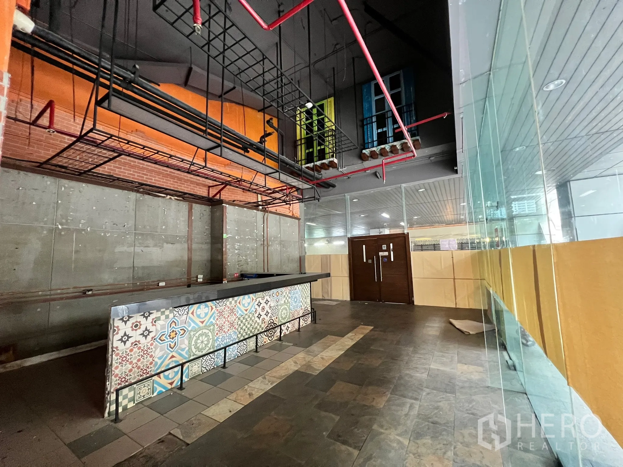 零售空间 出租在Watthana, Bangkok - 吧台旁临街玻璃与木门，上方金属吊架与外露管道。