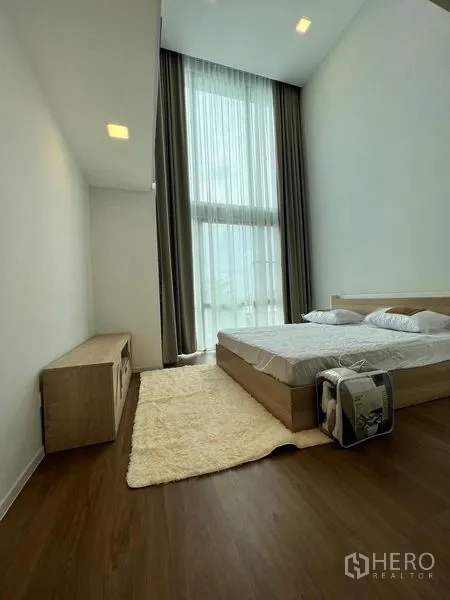 Detached House for rent - Bedroom with double-height ceiling, tall sheer curtains and warm wood flooring.
