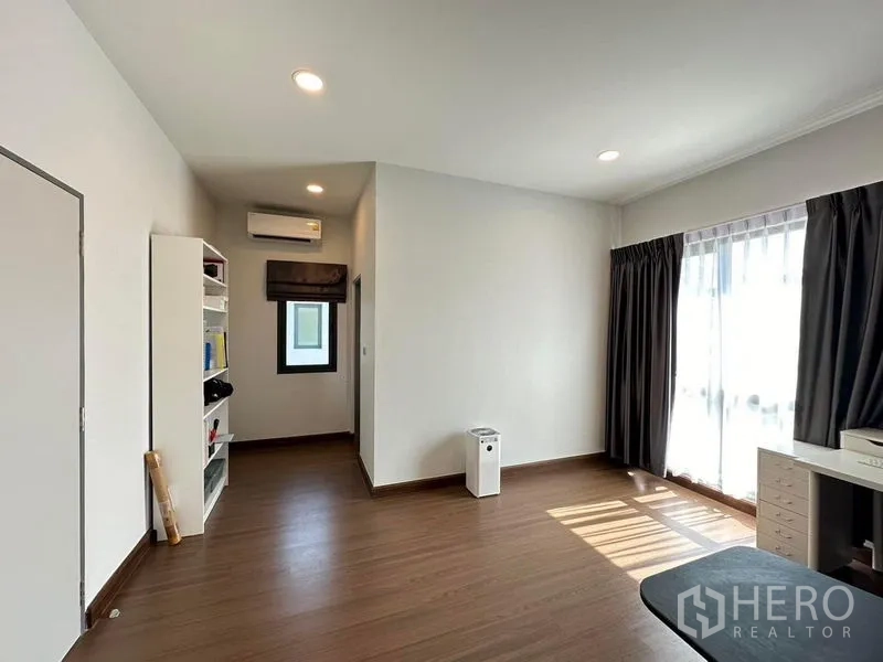 Detached House for rent in Bang Phli, Samut Prakan - Sunlit multipurpose room with wood floors, bookshelf and large window with blackout drapes.
