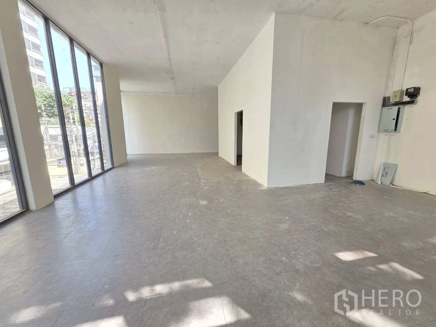 Retail Space for rent in Watthana, Bangkok - Open retail space with electrical panel and tall window frontage letting in light.