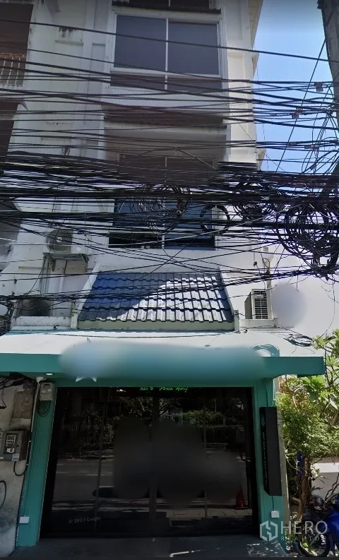店屋 出租在Watthana, Bangkok - 多层店铺外立面，玻璃门面与薄荷绿遮阳篷，街边电缆密集，位于曼谷艾卡迈区域