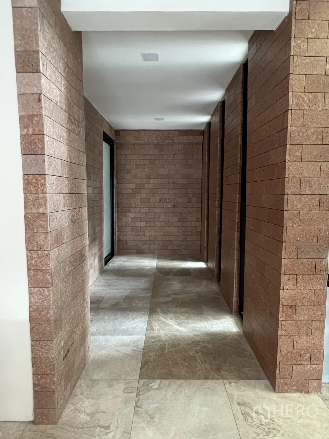 Detached House for rent or sale in Phra Khanong, Bangkok - Hallway with brick accent walls and polished stone floors.