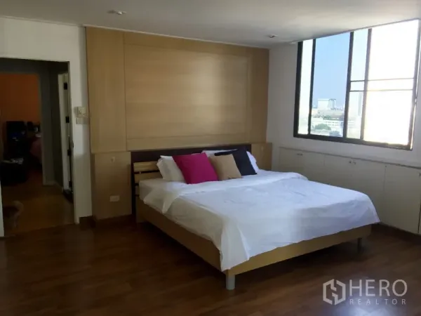 Condominium for rent or sale in Watthana, Bangkok - Large master bedroom with king bed, warm wood accents and wide city‑view windows.