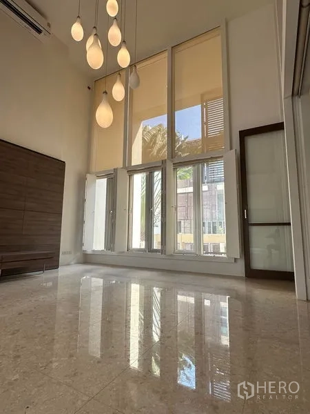 Townhouse for sale in Yan Nawa, Bangkok - Double-height living room with floor-to-ceiling windows, pendant lights and polished floors