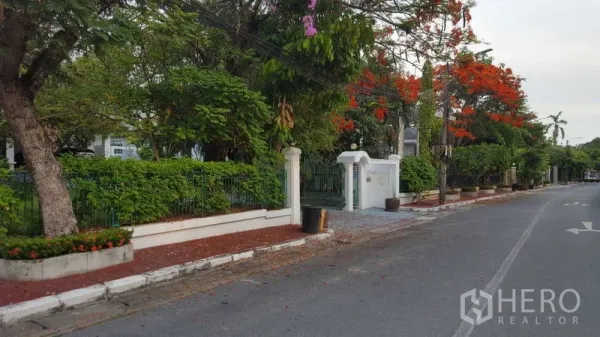 独立式住宅 出租在Bang Phli, Samut Prakan - 邦普里绿荫住宅街道与带门庭院的独栋房屋入口。