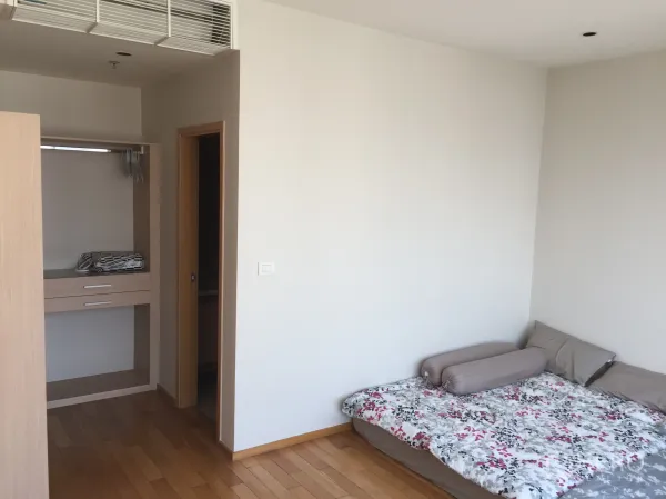 Condominium for rent or sale in Khlong Toei, Bangkok - Second bedroom with bed, open closet and light wood flooring.