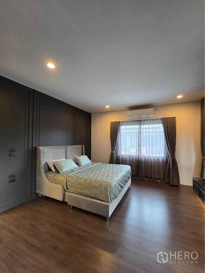 Detached House for rent in Bang Kapi, Bangkok - Master bedroom with large windows, curtains, and wood flooring.