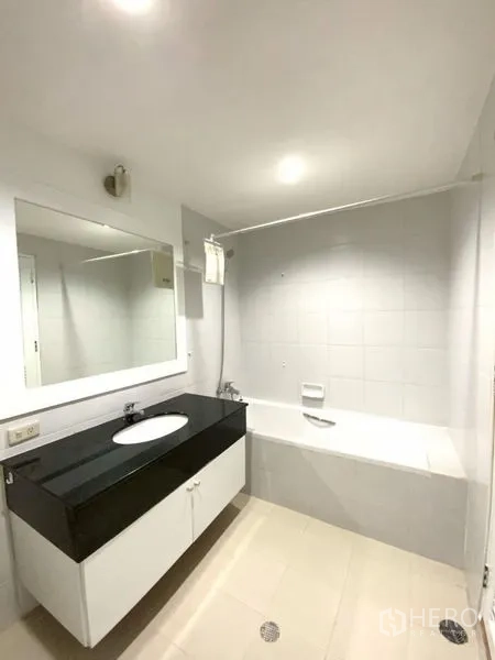 公寓 出租在Watthana, Bangkok - 整洁卫生间设大镜面、黑色台面洗手台及带淋浴的浴缸。