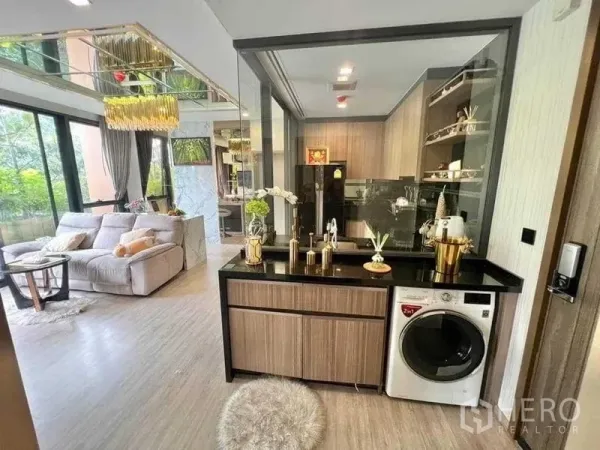 公寓 出售在Watthana, Bangkok - 客厅与玻璃隔断厨房相连，黑色台面与洗衣机，靠近大窗。