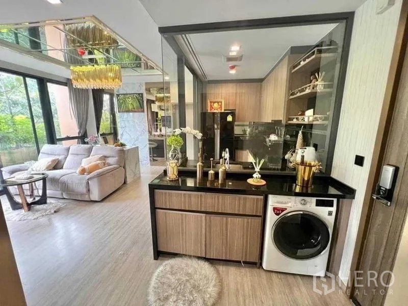公寓 出售在Watthana, Bangkok - 客厅与玻璃隔断厨房相连，黑色台面与洗衣机，靠近大窗。