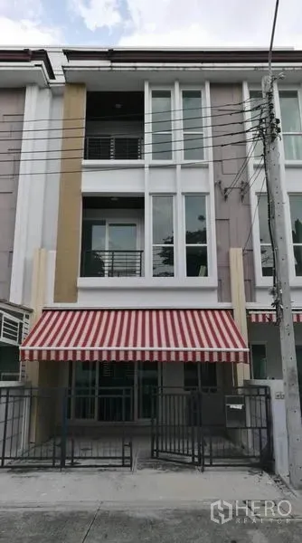 ทาวน์เฮาส์ ให้เช่าในWang Thonglang, Bangkok - ด้านหน้าอาคารทาวน์เฮ้าส์ 3 ชั้น หลังคากันสาดลายแดงขาว พร้อมที่จอดรถมีรั้ว