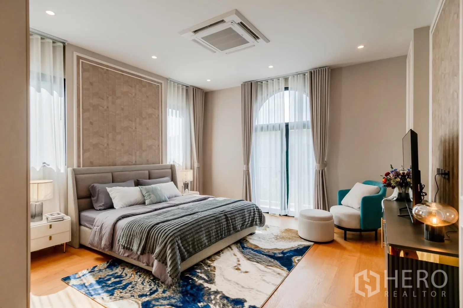 Detached House for rent or sale in Saphan Sung, Bangkok - Large bedroom with patterned rug, big bed and tall draped windows.