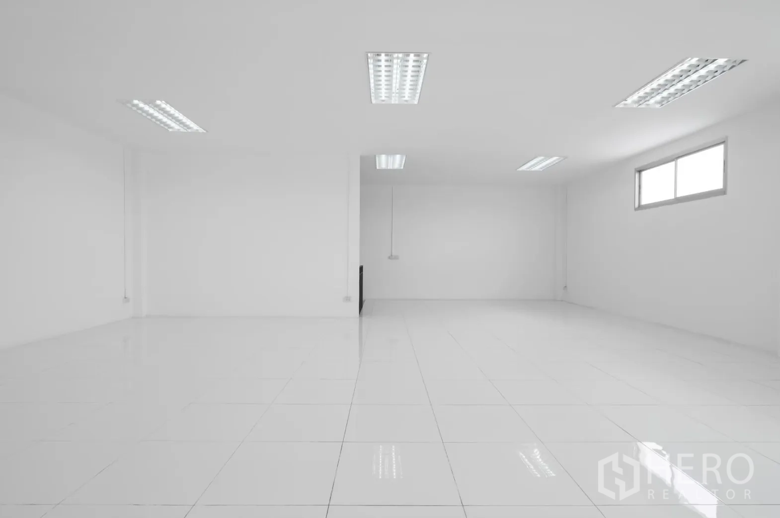Factory for rent in Pathum Thani - Empty white office room with fluorescent lighting and a single window.