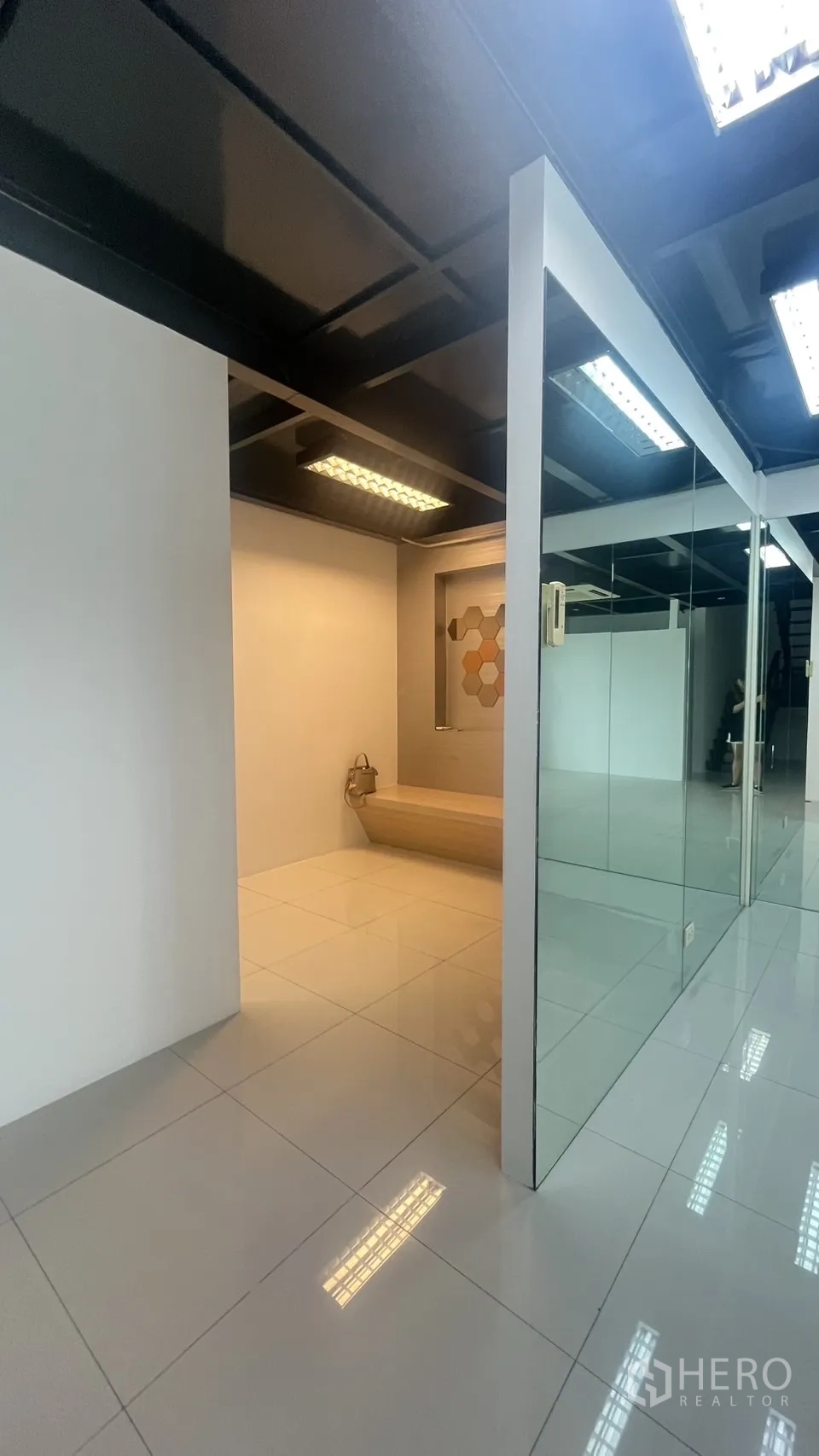 Office Space for rent in Khlong Toei, Bangkok - Clean tiled office area with a glass partition, black ceiling lighting, and a built-in bench alcove.
