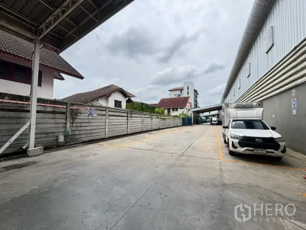 Warehouse for rent in Bang Sue, Bangkok - Exterior loading driveway beside the warehouse with marked parking bays and box trucks.