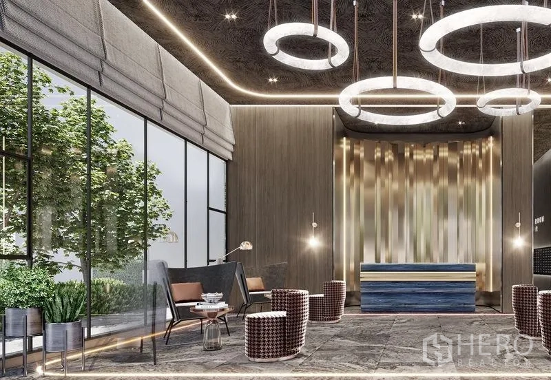 公寓 出售在Khlong Toei, Bangkok - 设计感大堂，环形吊灯、接待台与落地窗，窗外绿意景观。